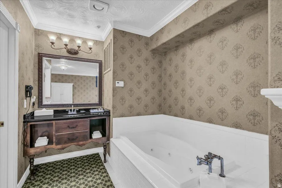 Bathroom with vanity, crown molding, and a whirlpool tub