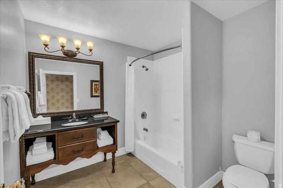 Full bath with shower / bathtub combination with curtain, vanity, and light tile patterned floors