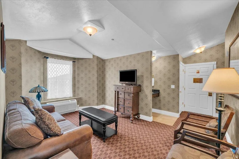 Living area with wallpapered walls, light colored carpet, and a packaged terminal hvac unit