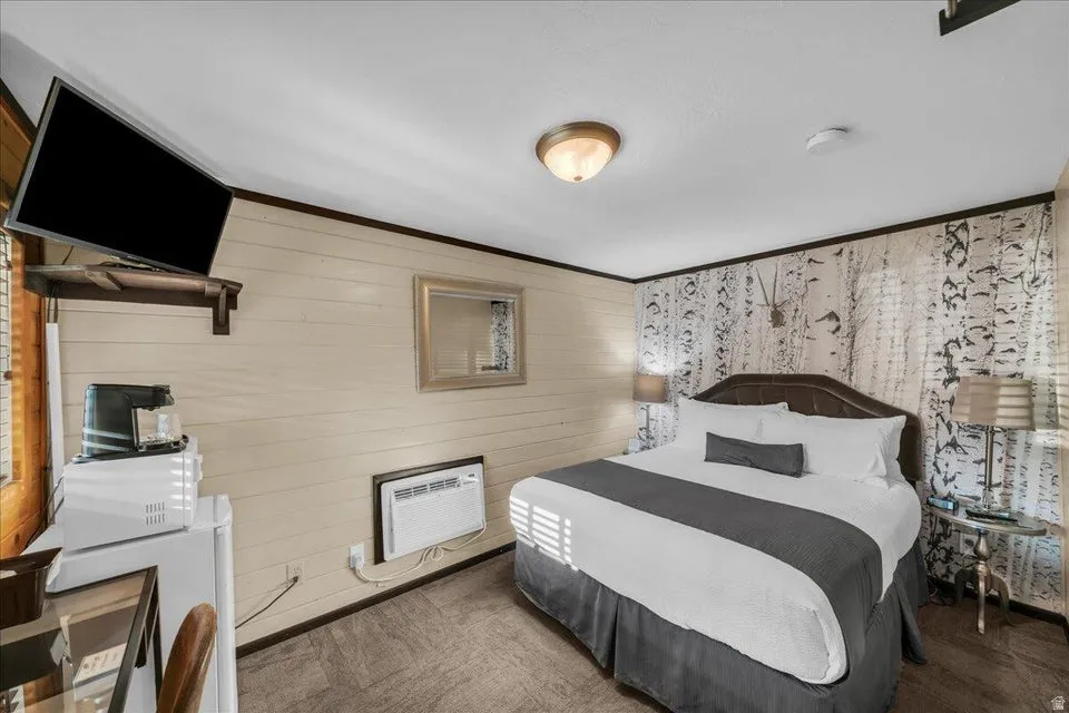 Carpeted bedroom with wooden walls and ornamental molding