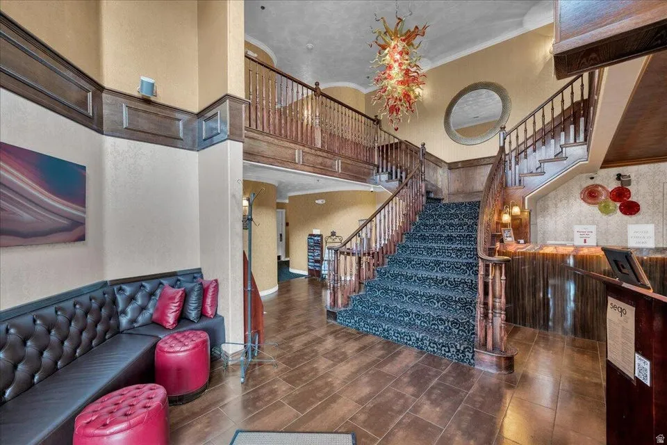 Staircase with a high ceiling, ornamental molding, and wood finish floors