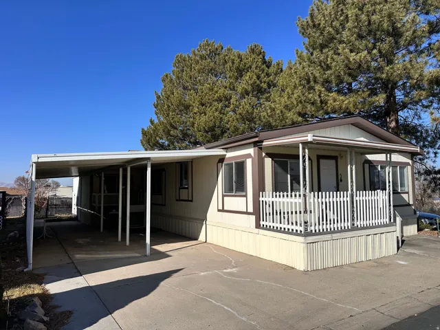 Manufactured / mobile home with a carport, driveway, and covered porch