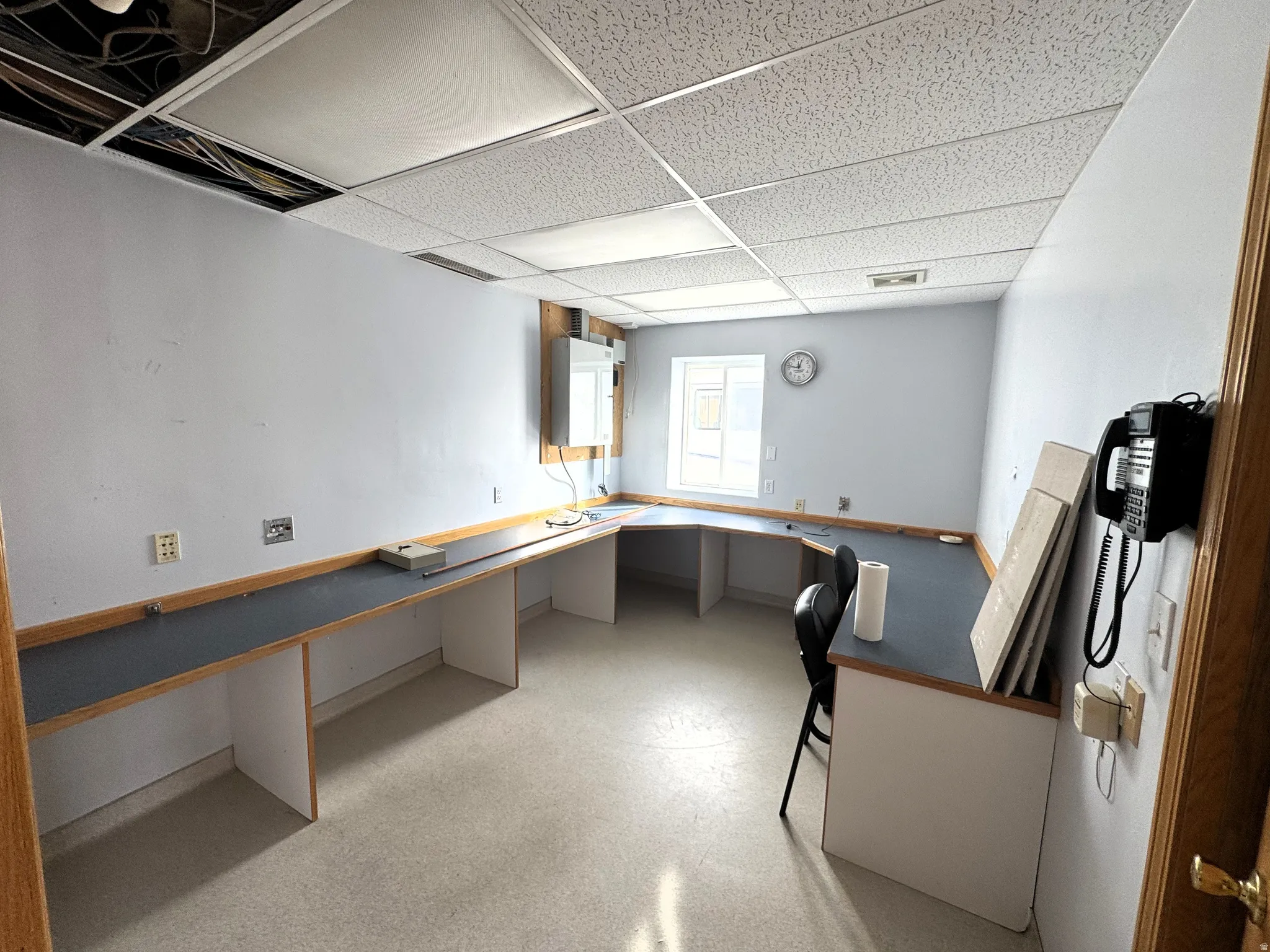 Unfurnished office with built in desk, a drop ceiling, and water heater