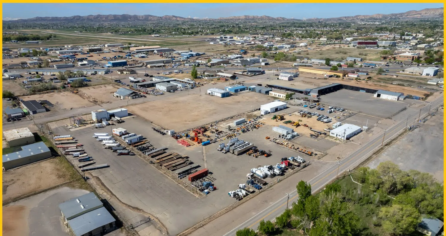Aerial view of property and surrounding area featuring industrial structures and a mountainous background