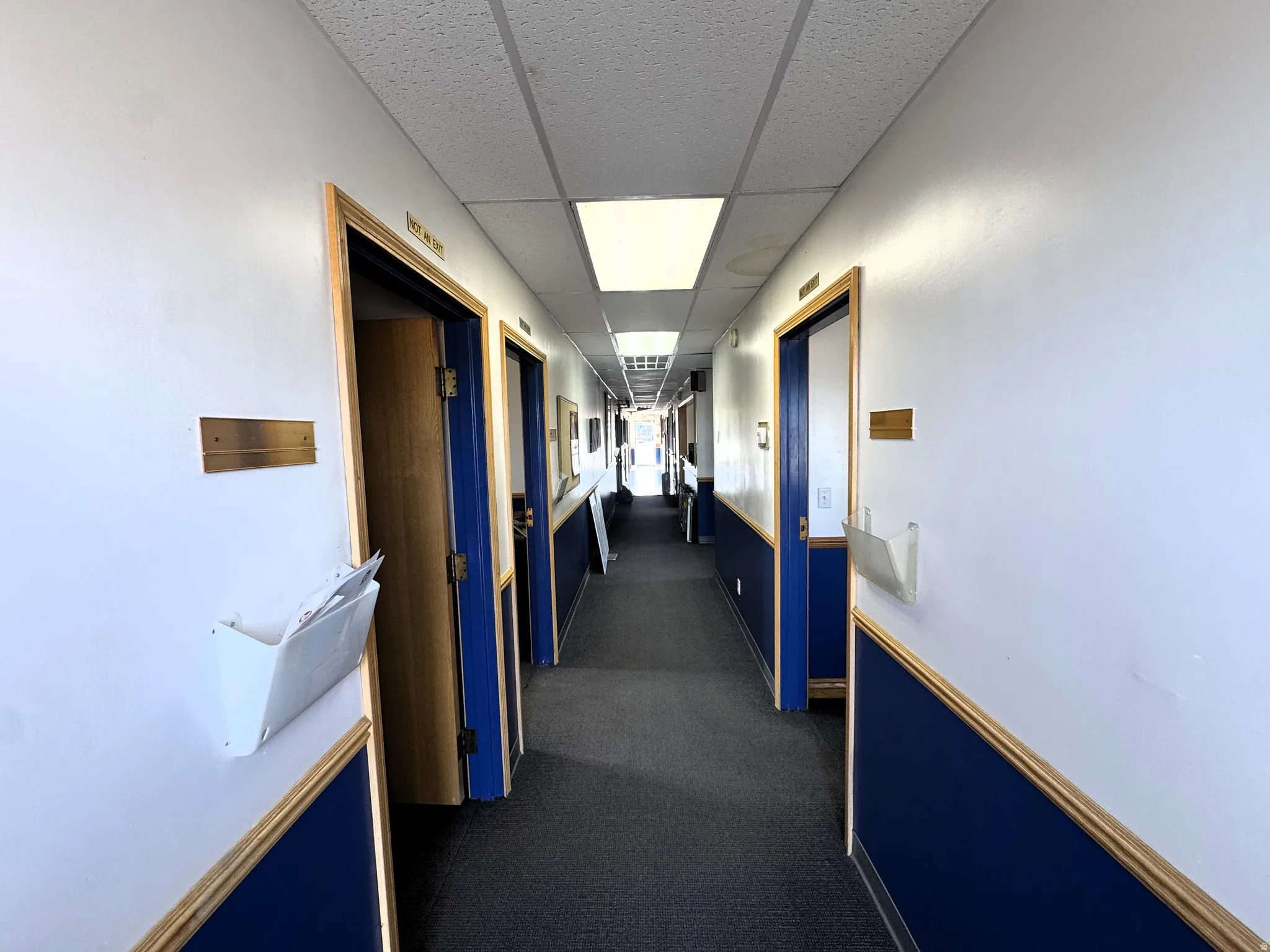 Hallway featuring a drop ceiling and dark colored carpet