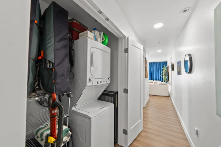 Laundry area with stacked washer / dryer, light wood-style floors, and recessed lighting