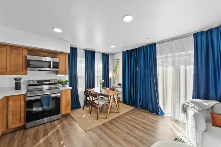 Kitchen with stainless steel appliances, wood finish cabinetry, light wood-type flooring, light stone counters, and recessed lighting