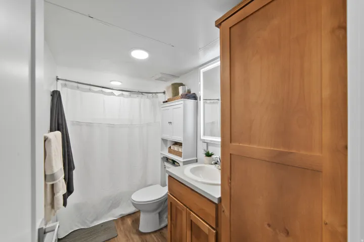 Bathroom featuring a shower with shower curtain, vanity, and dark wood finished floors