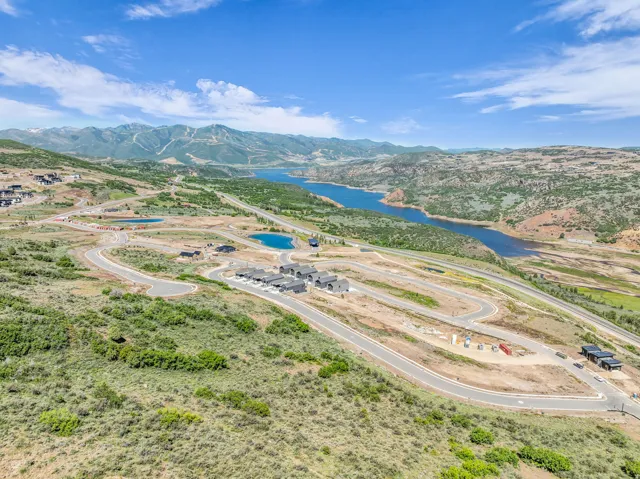 Expansive terrain featuring a deep blue reservoir, distant mountains, and developed roadways