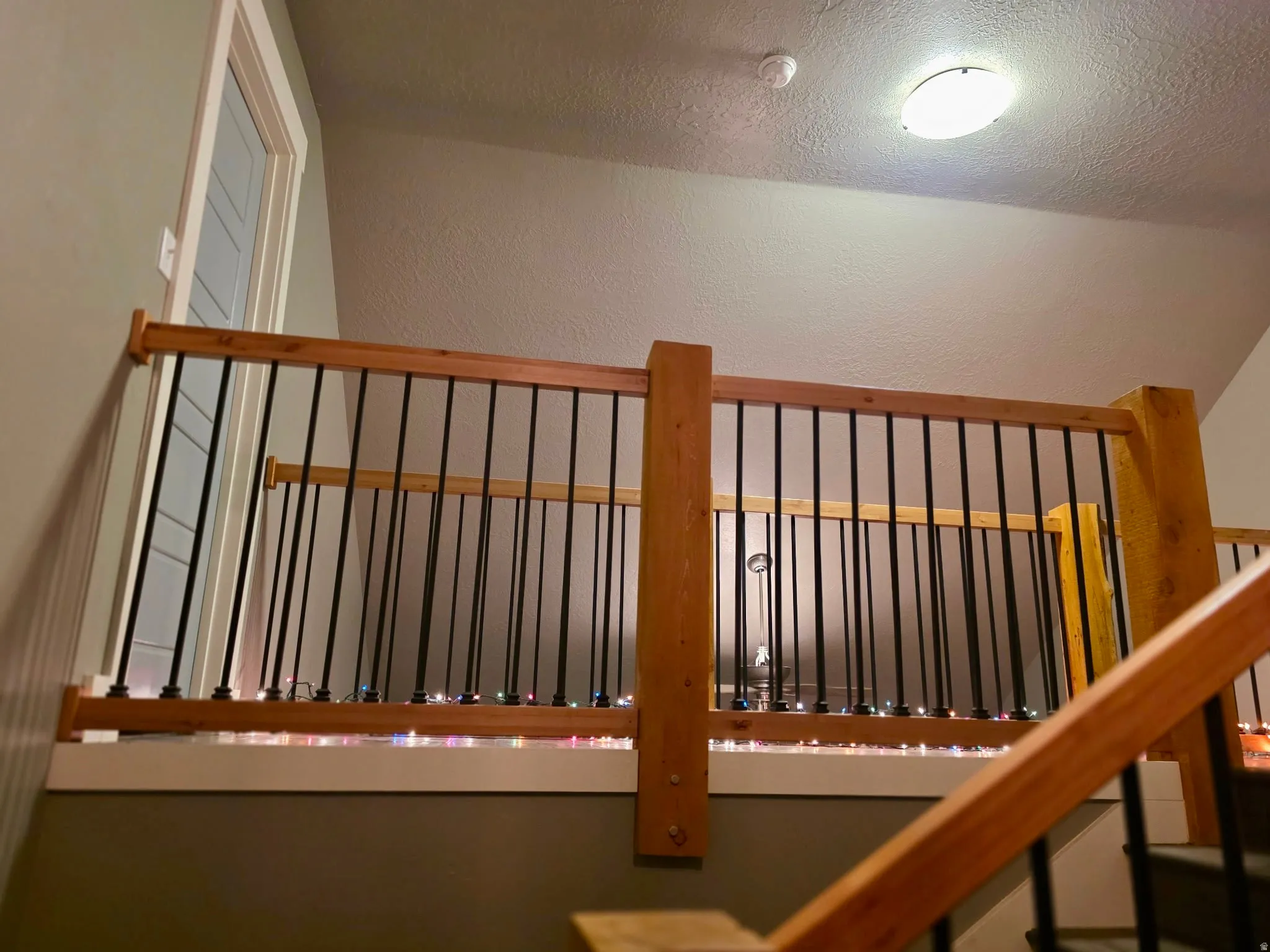 Staircase featuring a textured wall and a textured ceiling