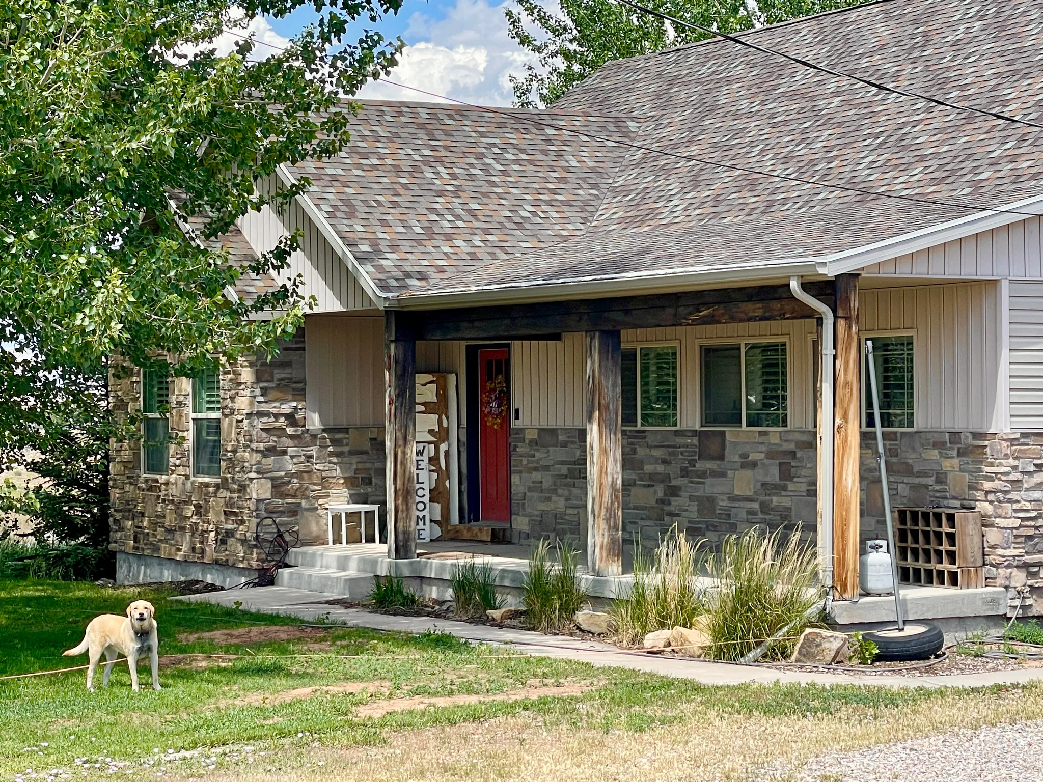Stone and siding exterior with a covered porch featuring wood posts