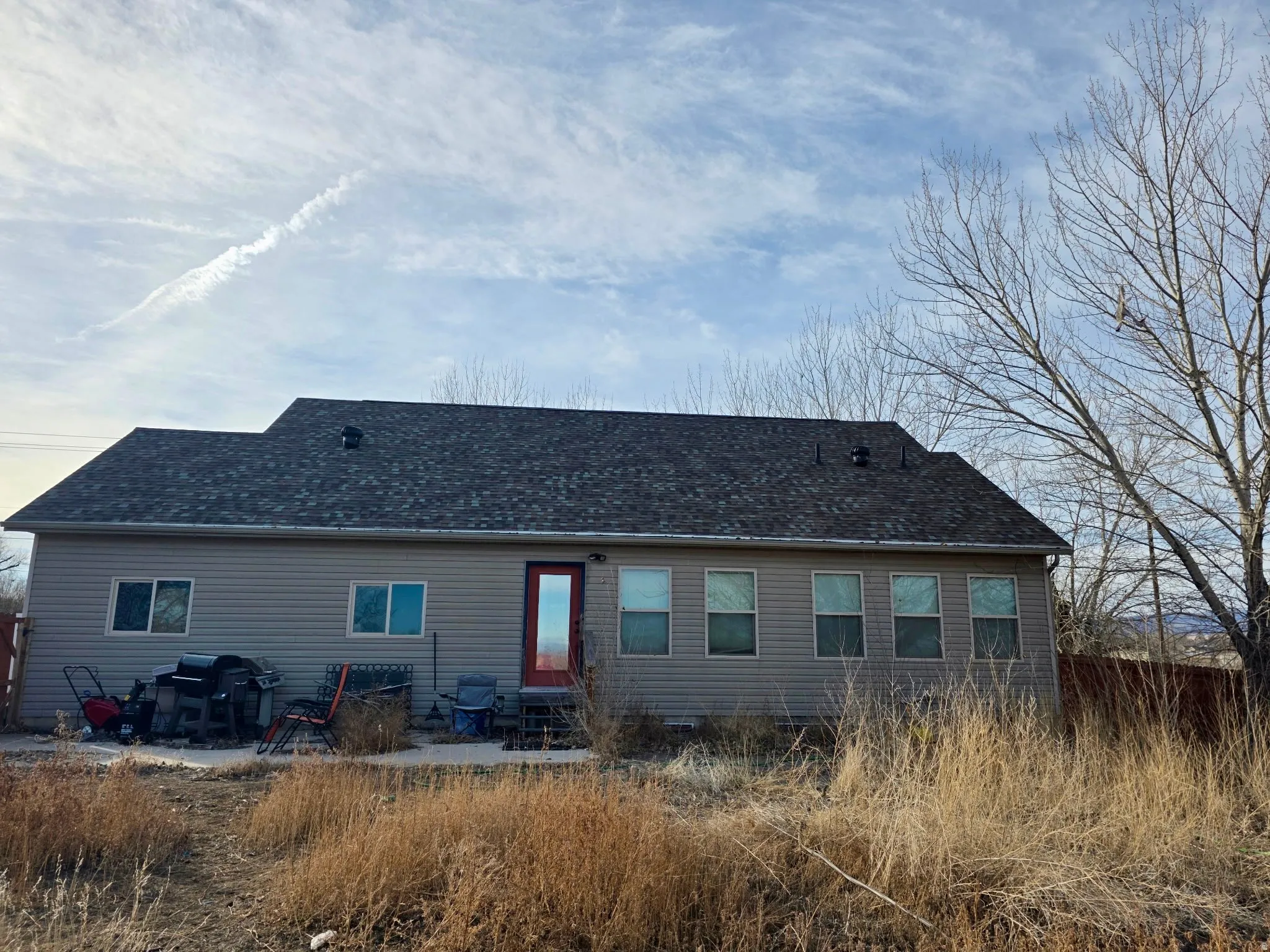 Rear view of house featuring a patio area, entry steps, and a shingled roof