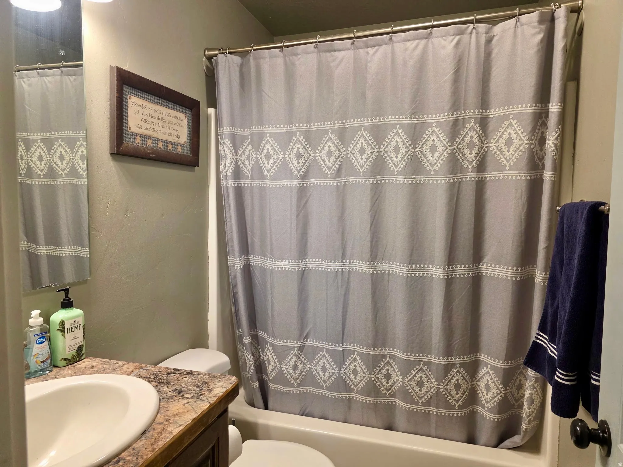 Bathroom featuring vanity, shower / bathtub combination with curtain, and a textured wall