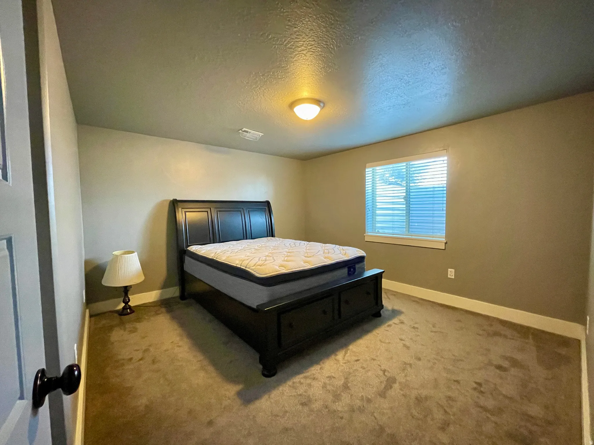 Bedroom with light colored carpet and a textured ceiling