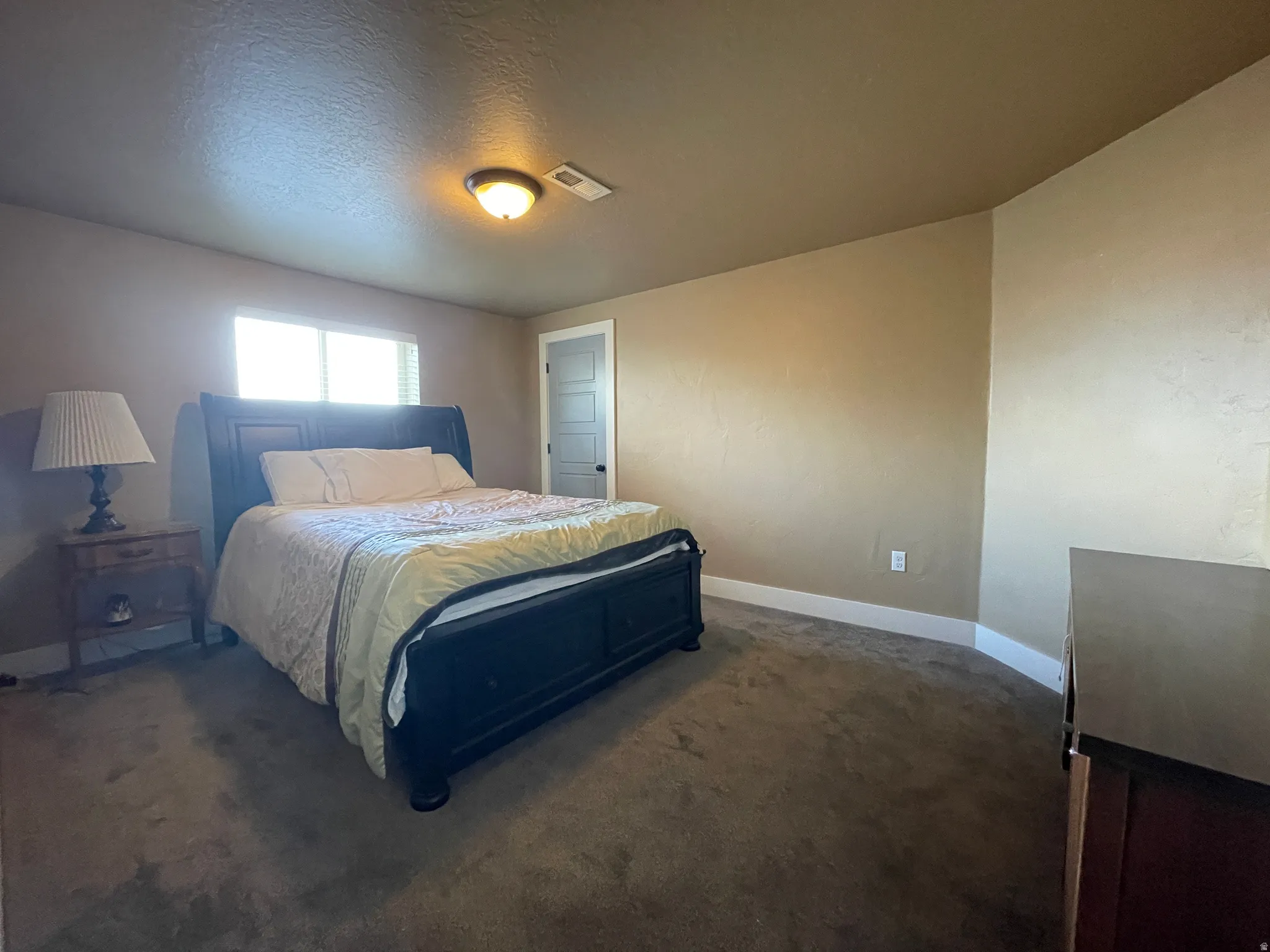 Bedroom with dark carpet and a textured ceiling