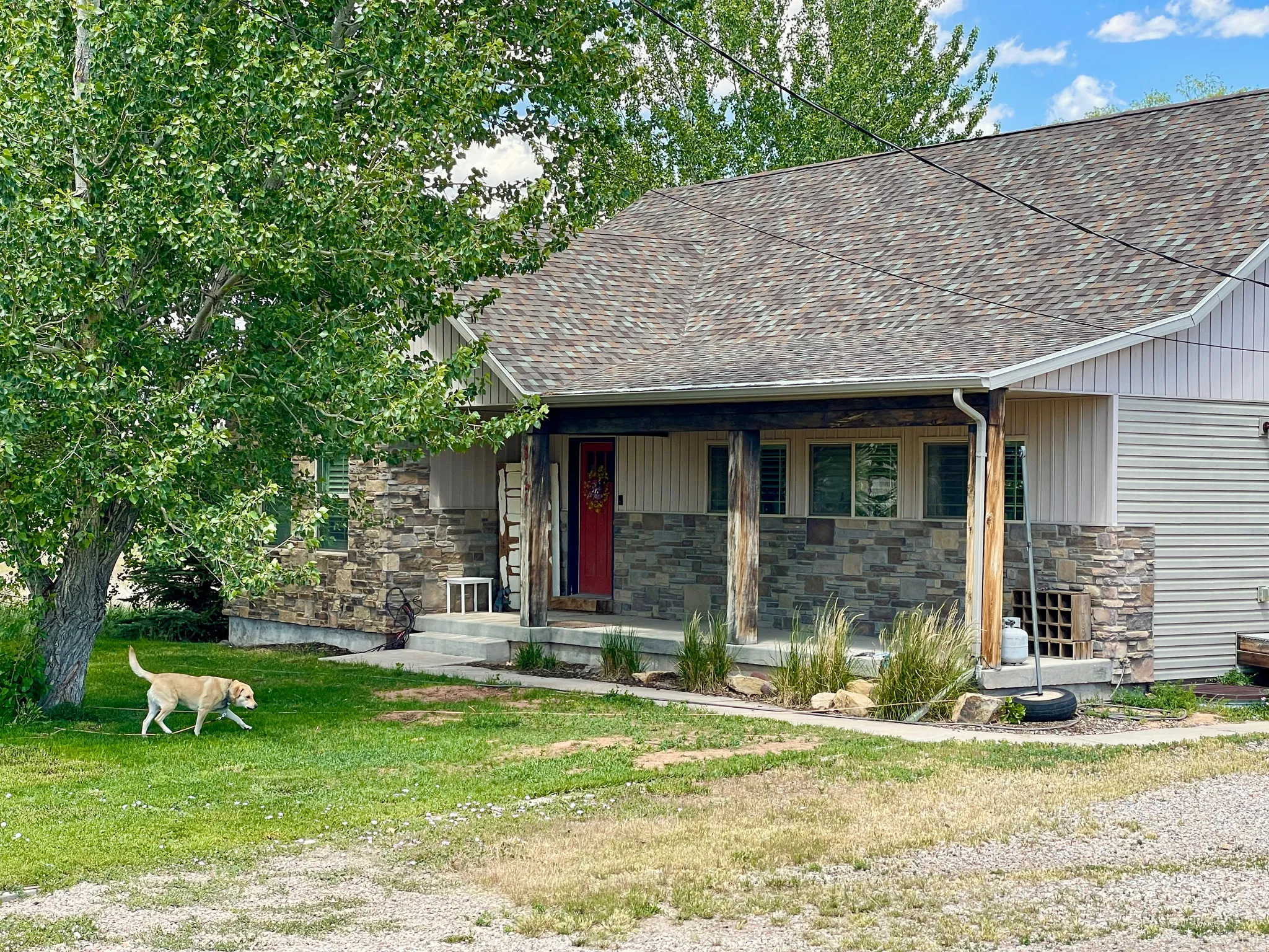 Stone veneer and siding exterior with a covered porch featuring natural wood columns