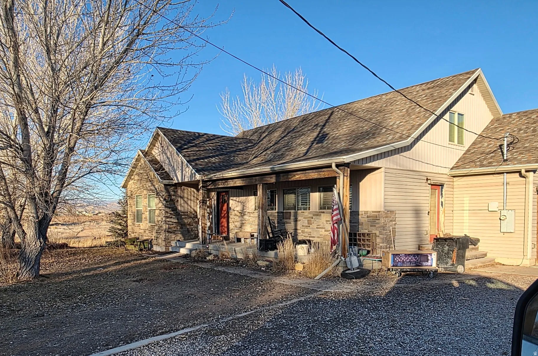 View of front of home with a shingled roof, stone siding, and a porch