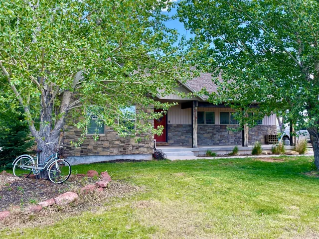 Stone and siding exterior with a covered porch featuring natural wood pillars