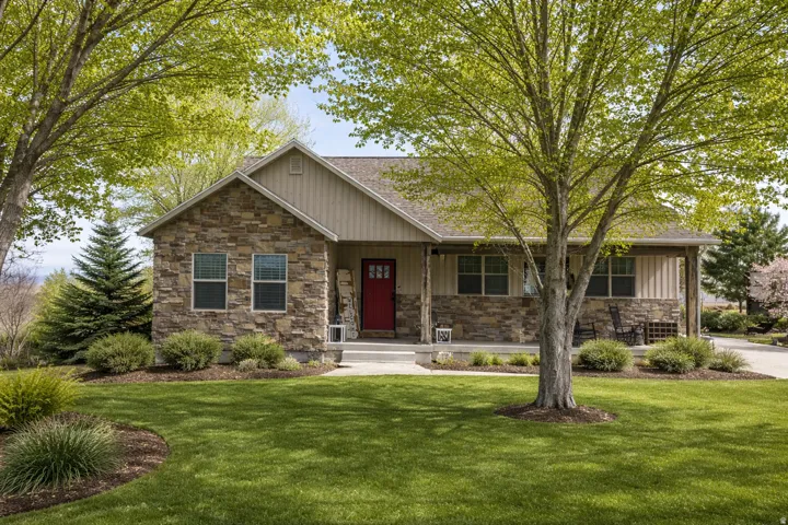 View of front of house with a front lawn, stone siding, and a porch. Edited with AI to show springtime