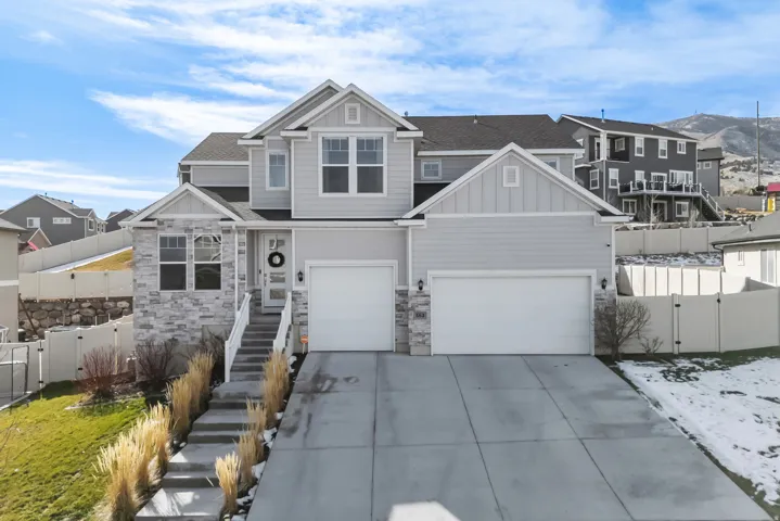View of front facade with a gate, stone siding, concrete driveway, and board and batten siding