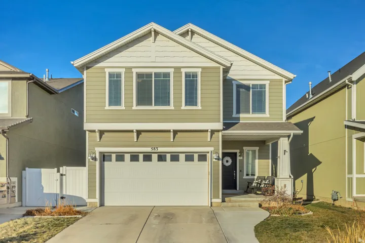 Craftsman inspired home with an attached garage, driveway, and a gate