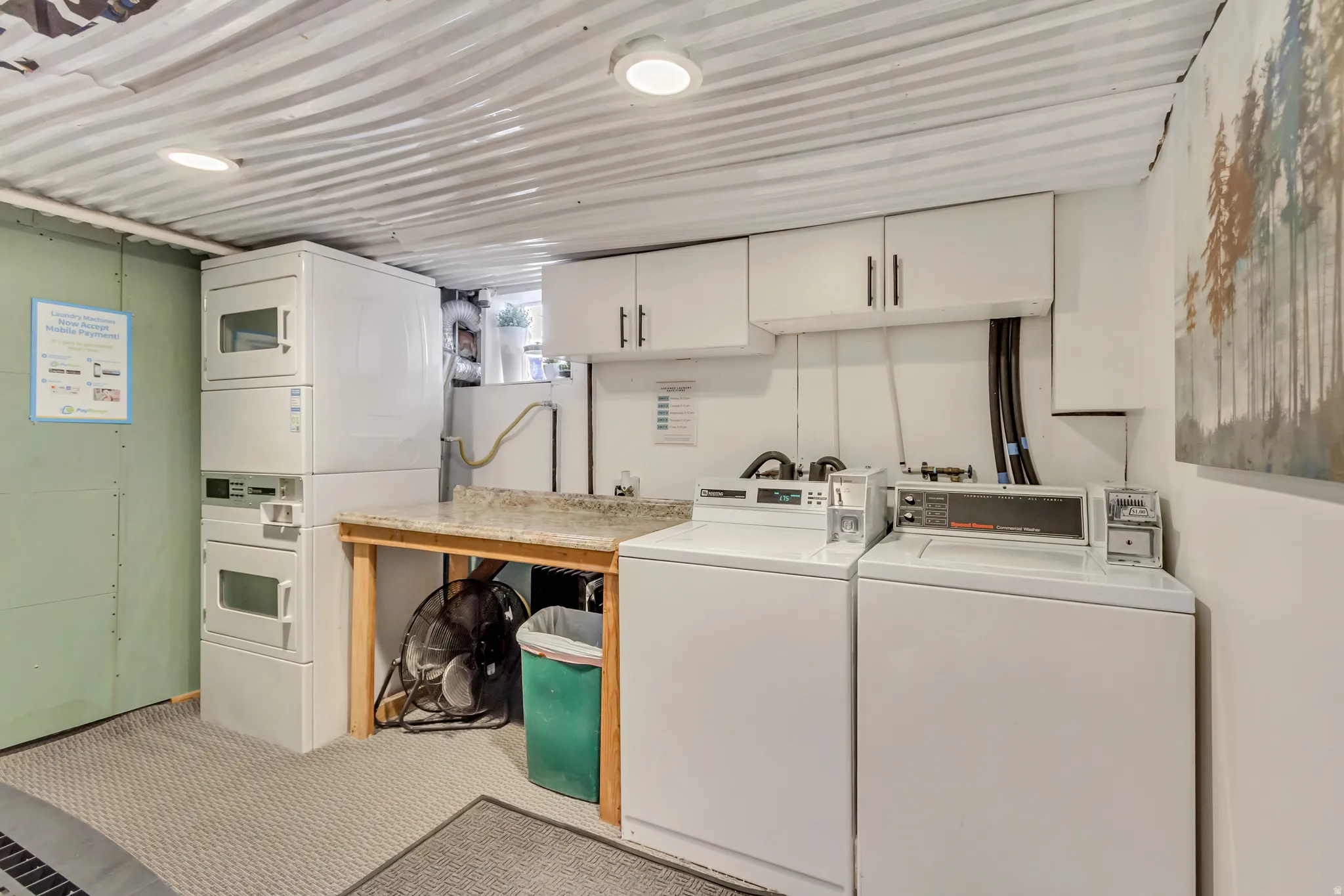 Shared laundry room with stacked dryers and two washers. Coin or credit card operated
