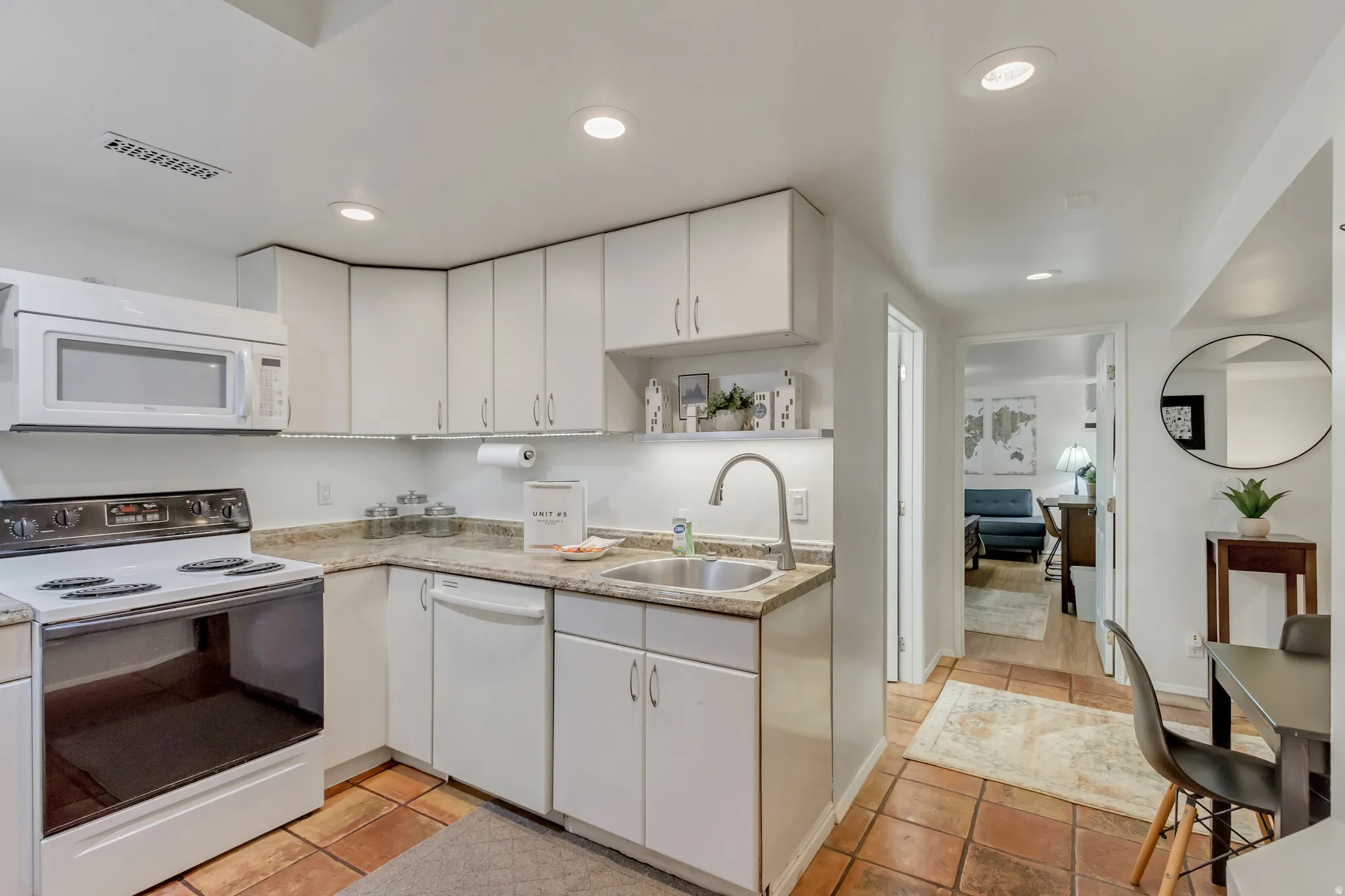 Apt. #5 Kitchen with white appliances, white cabinets, and tiled floor.