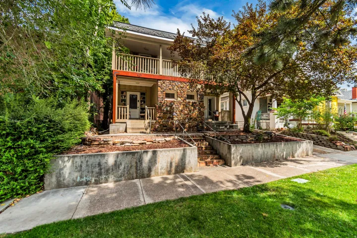 Stone facade with dual-level balconies, concrete retaining walls, and a manicured lawn
