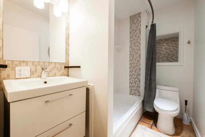 Apt. #3 Full bath with vanity, shower / tub combo, tile patterned flooring, and backsplash