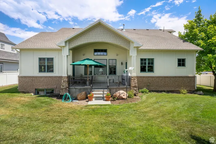 Back of house featuring board and batten siding, roof with shingles, brick siding, and a patio