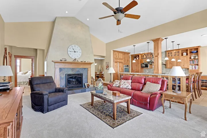 Living area with high vaulted ceiling, carpet, a ceiling fan, a tile fireplace, and recessed lighting