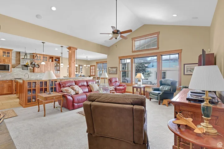 Living room featuring high vaulted ceiling, a ceiling fan, light carpet, decorative columns, and recessed lighting