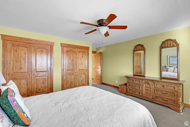 Bedroom with carpet floors, two closets, and ceiling fan