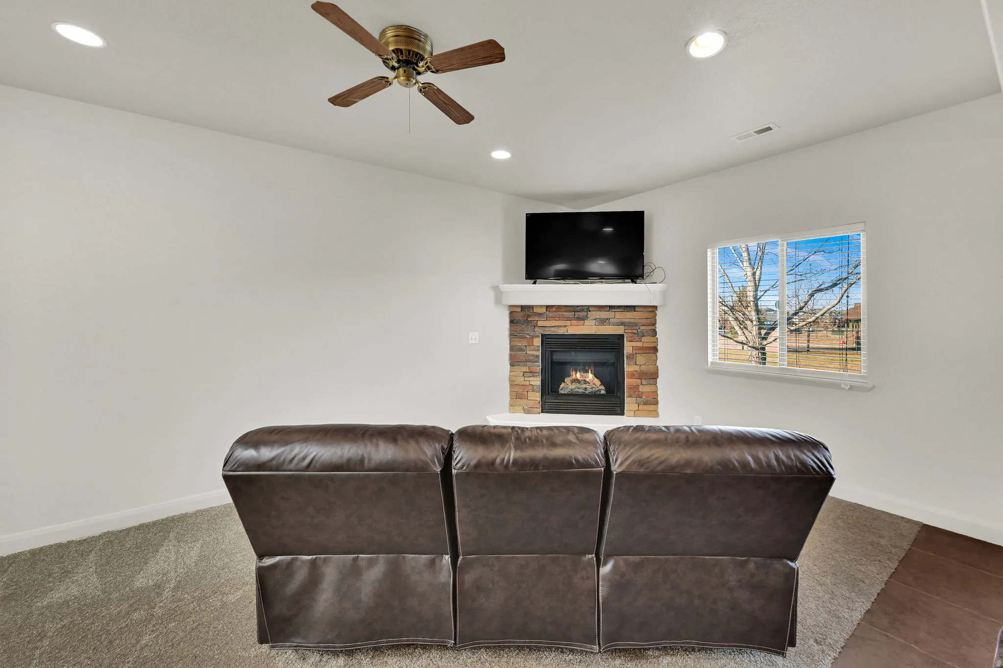 Living room with a fireplace, recessed lighting, and ceiling fan