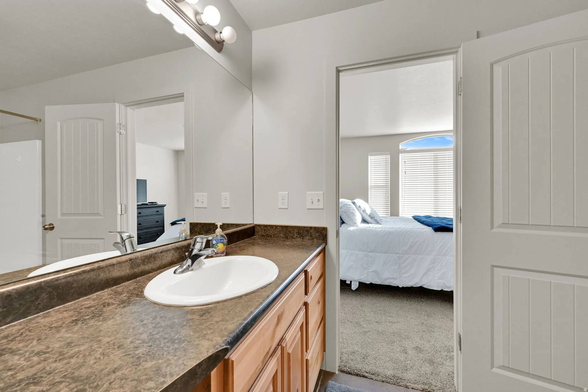 Bathroom with vanity, connected bathroom, and light colored carpet