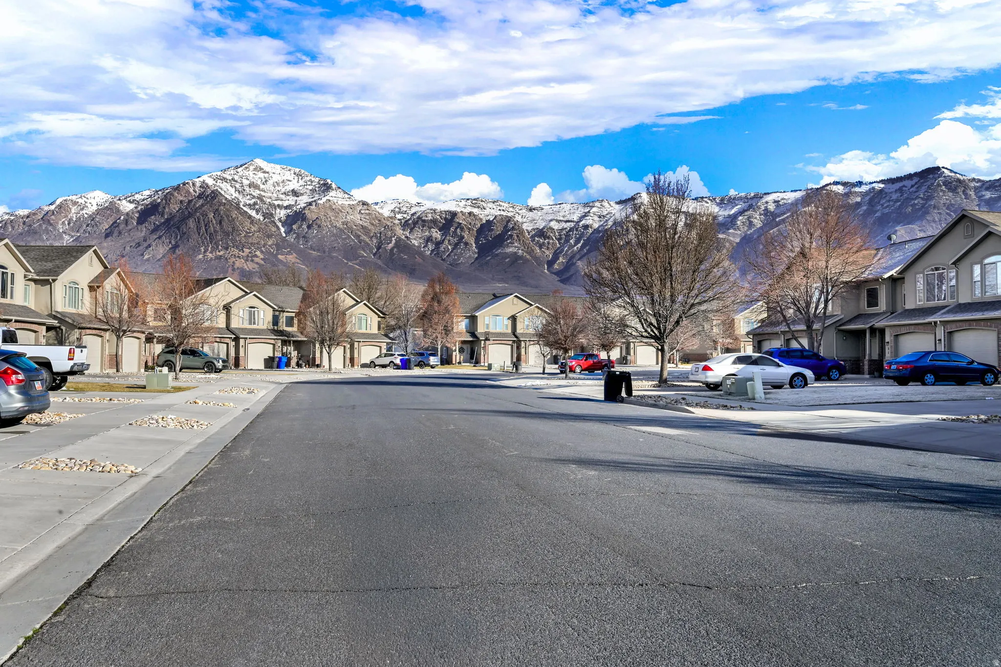 View of asphalt road featuring a mountain view, a residential view, curbs, and sidewalks