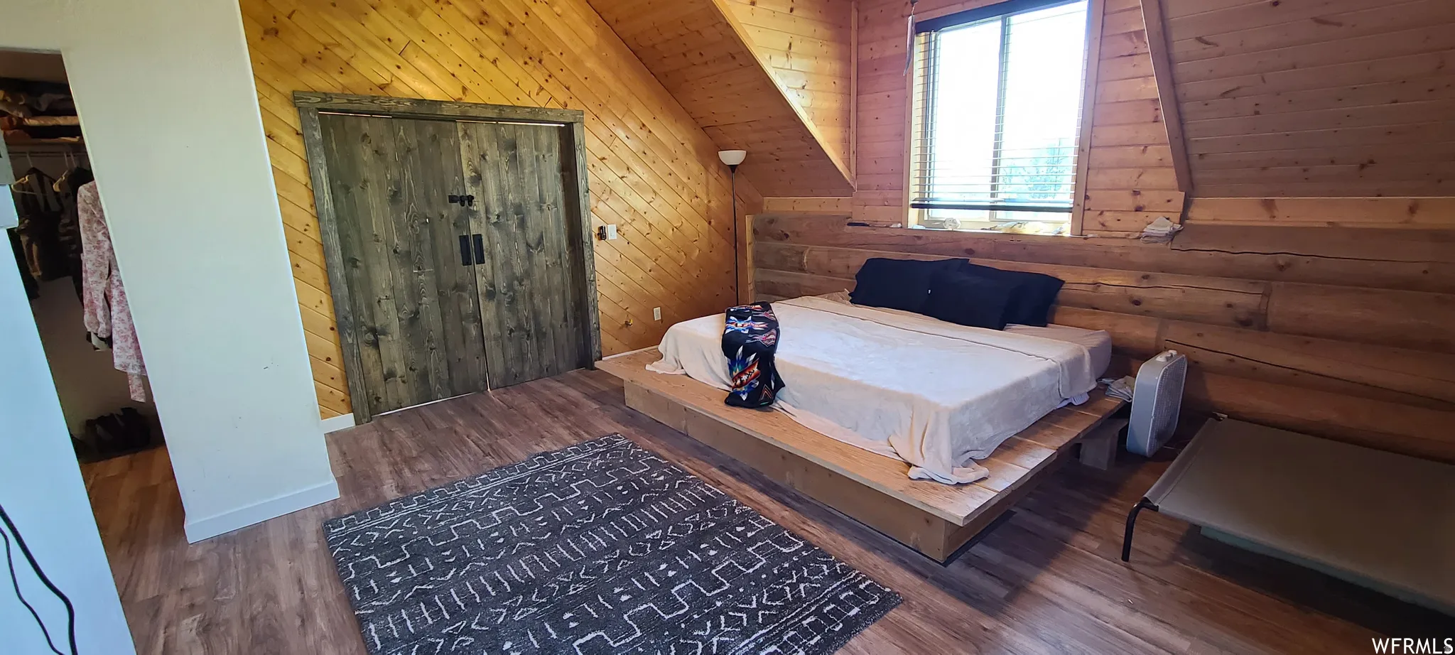 Bedroom with wood finished floors and wooden walls