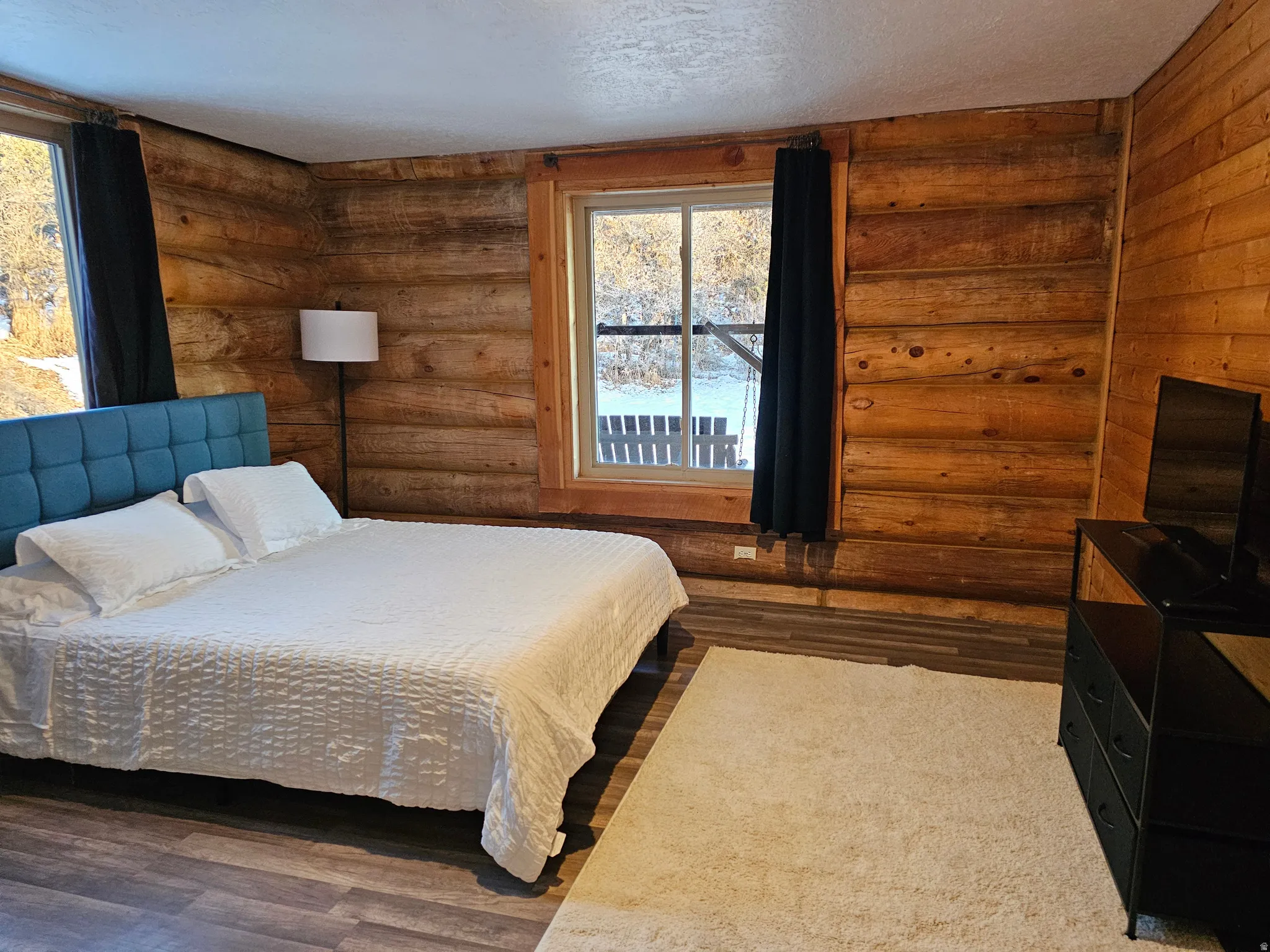 Bedroom featuring rustic walls, wood finished floors, and a textured ceiling