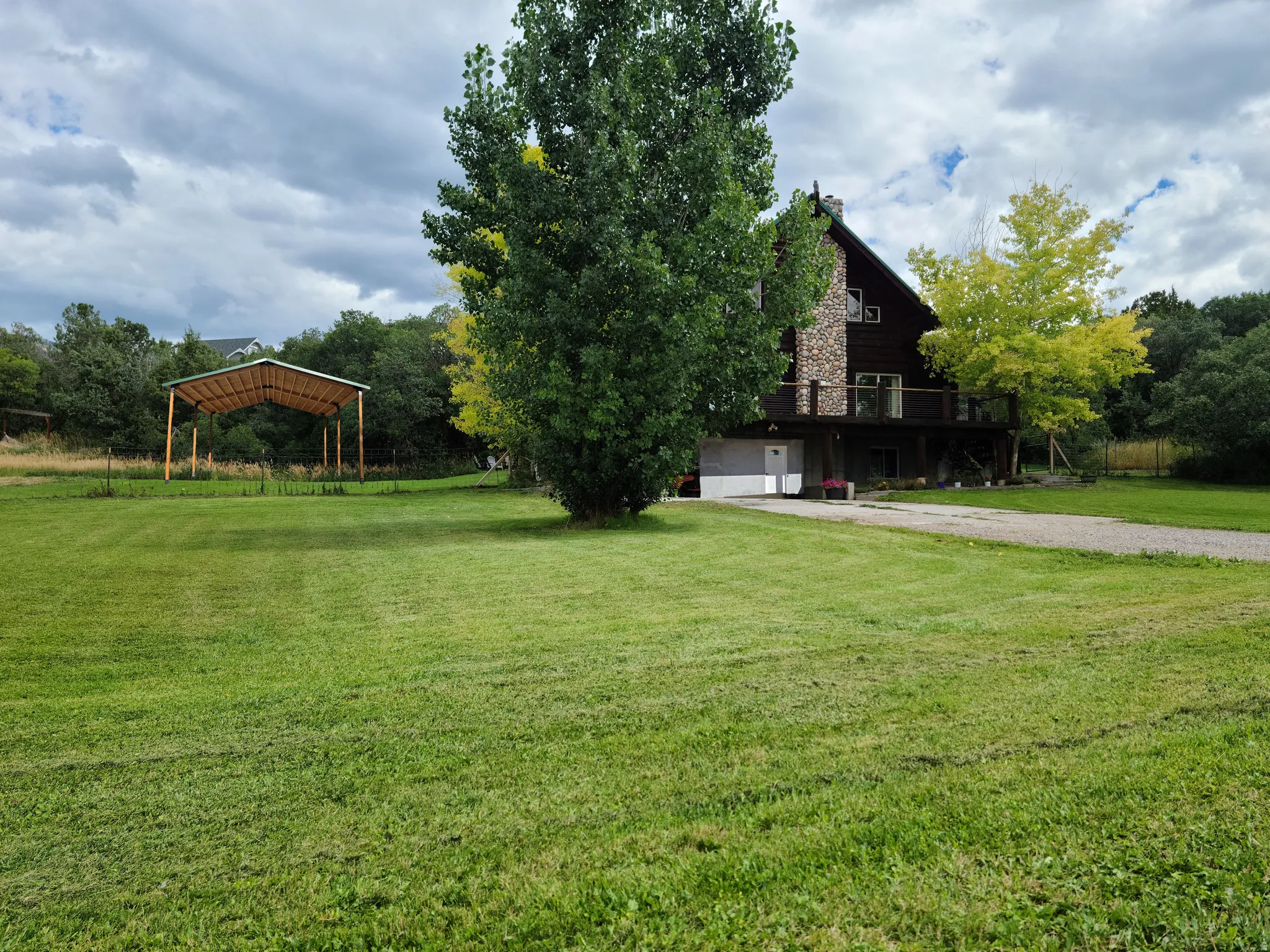 View of green lawn with a wooden deck and driveway