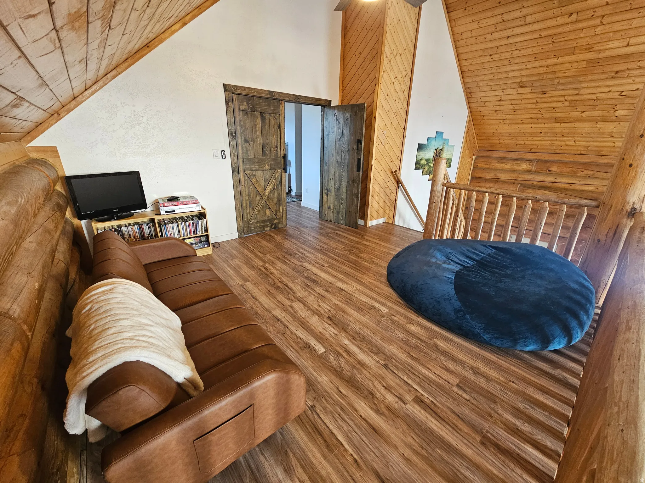 Living room featuring a vaulted wooden ceiling, wood finished floors, and log walls