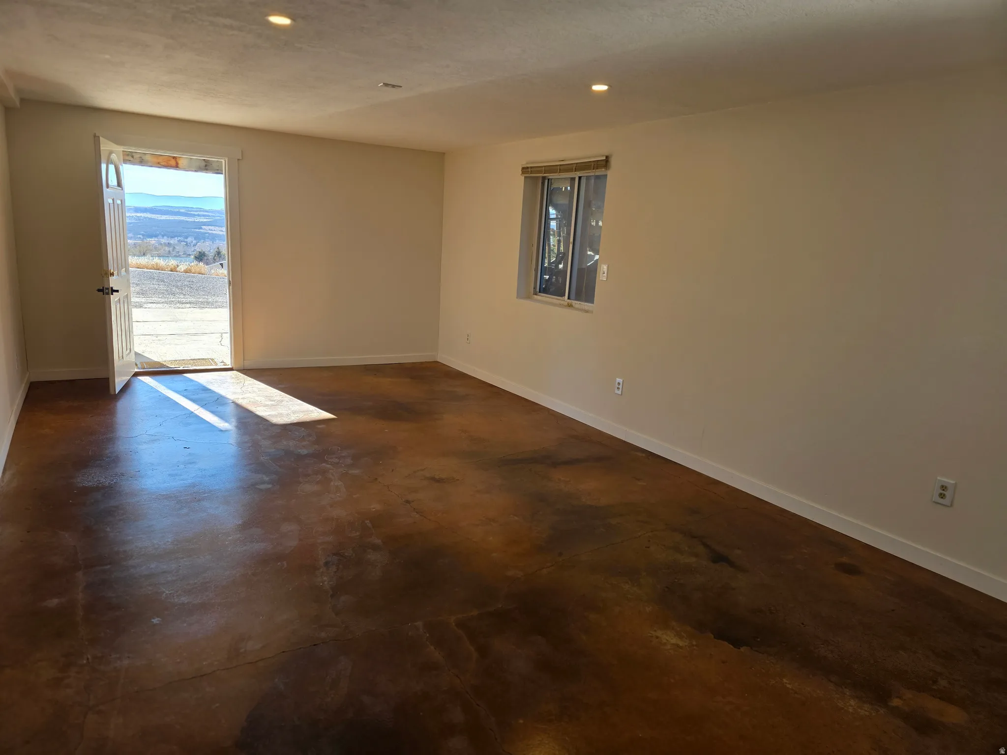 Spare room with finished concrete floors, plenty of natural light, a textured ceiling, and recessed lighting