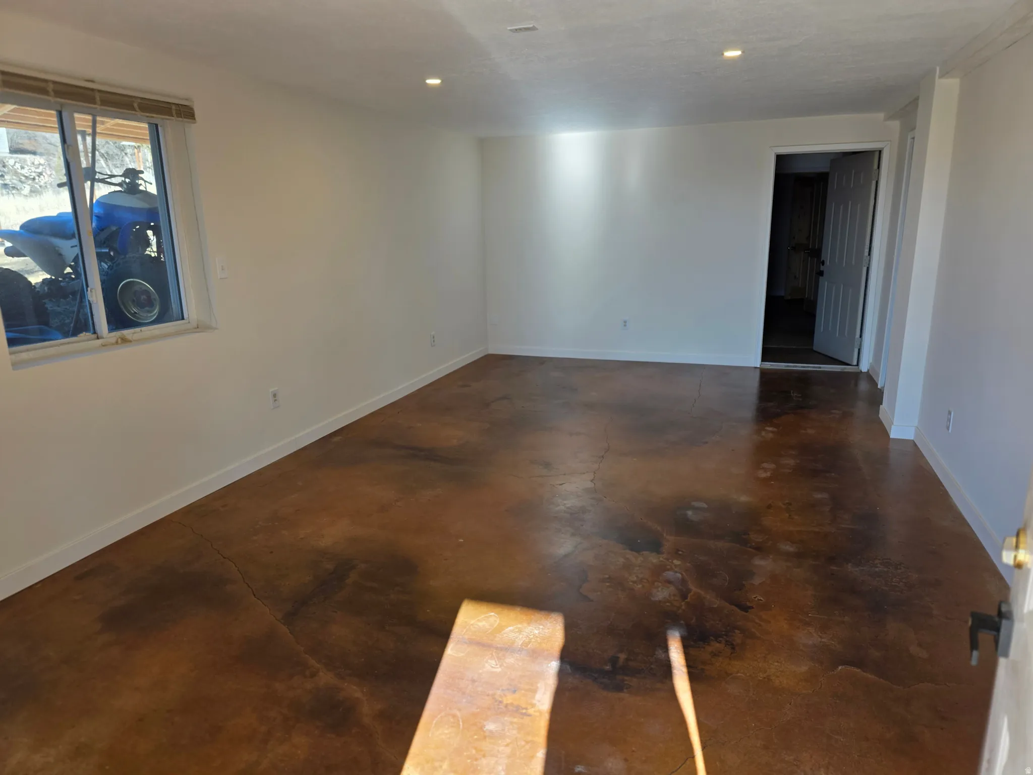 Unfurnished room with finished concrete flooring and recessed lighting