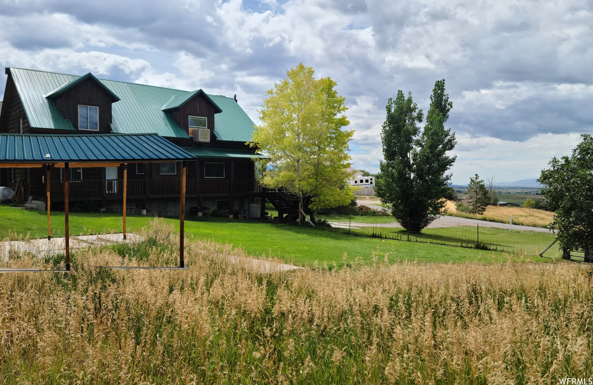 Rear view of house featuring a porch, a metal roof, a view of rural / pastoral area, and oil tank