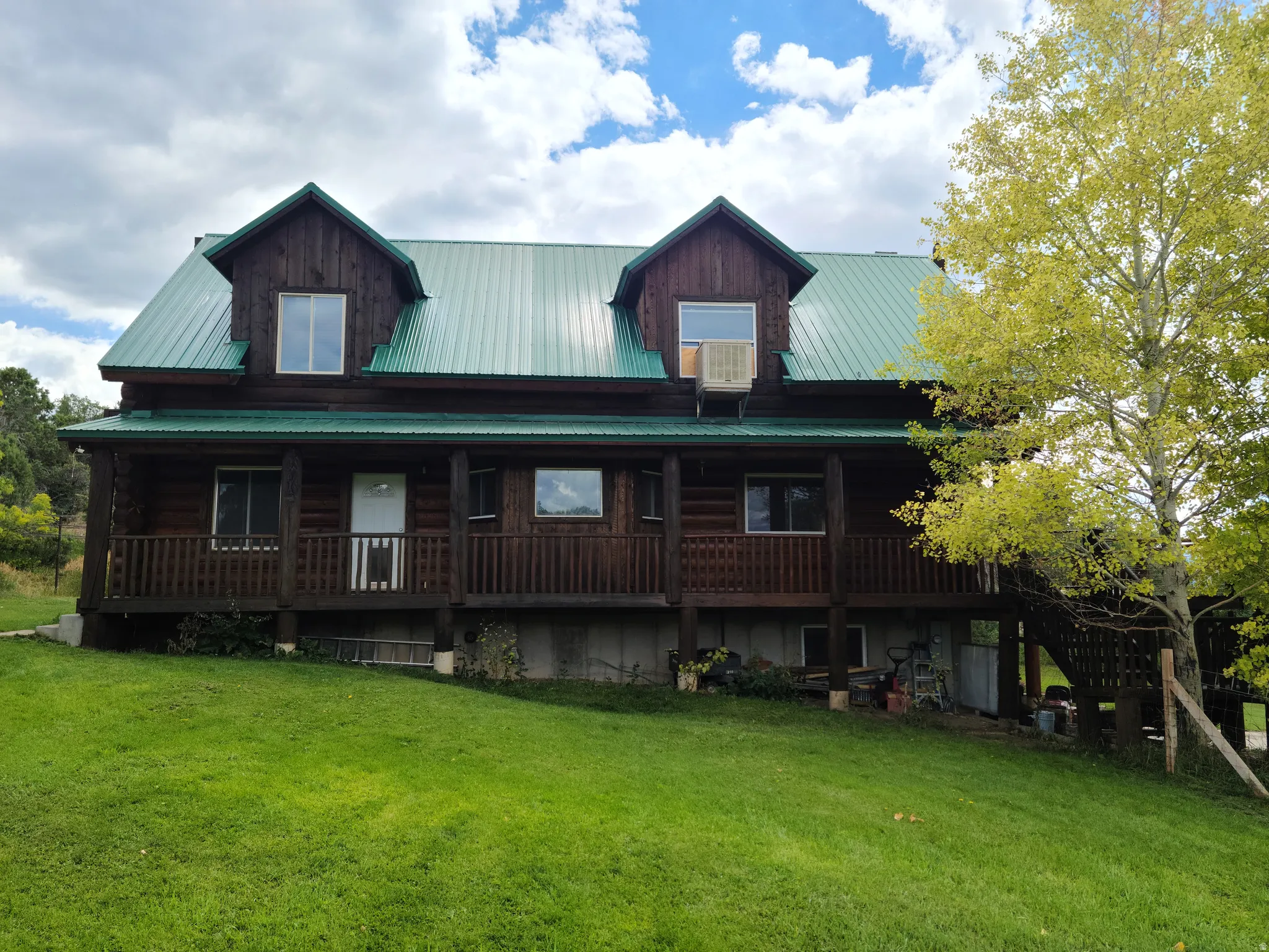 View of front facade with a front lawn, covered porch, and a metal roof