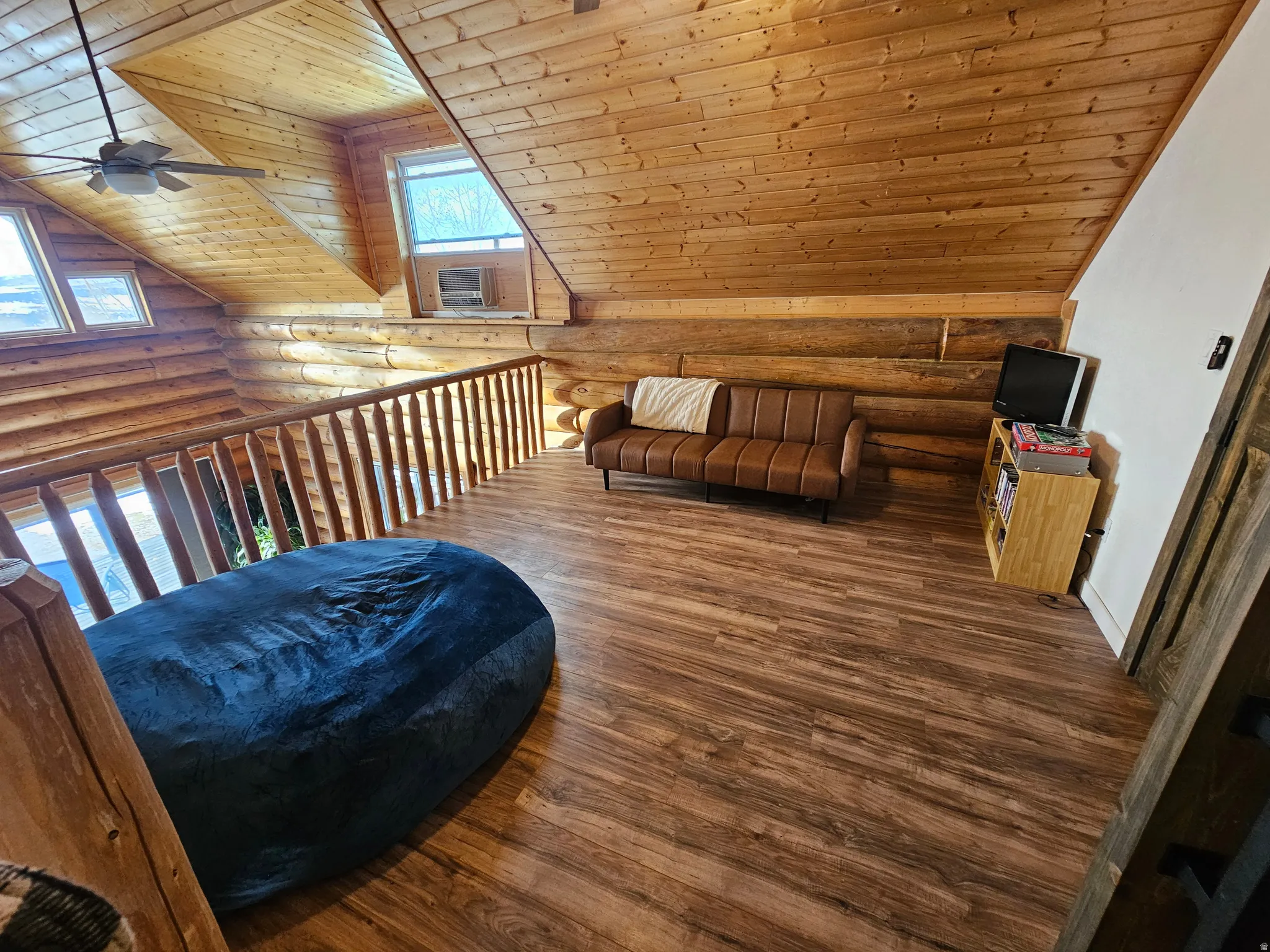 Additional living space featuring log walls, a vaulted wooden ceiling, a ceiling fan, and hardwood / wood-style flooring