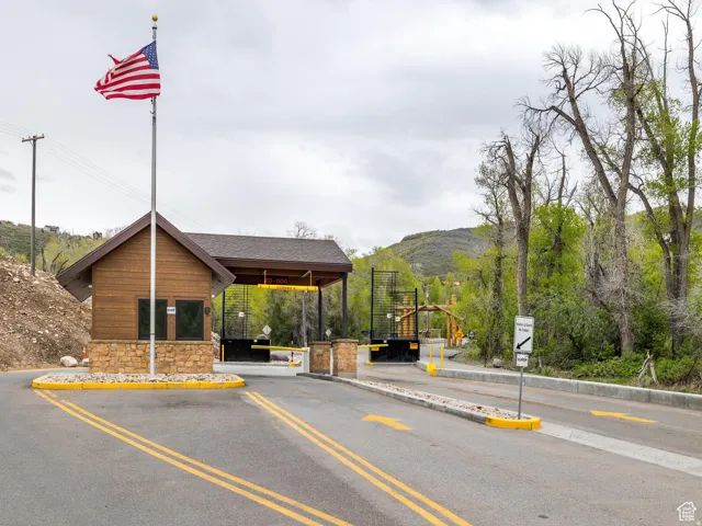 View of asphalt street featuring a gated entry, curbs, and a mountain view