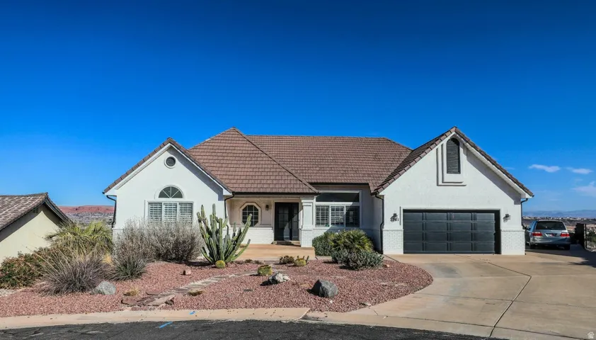 View of front of house with concrete driveway, stucco siding, brick siding, and a garage