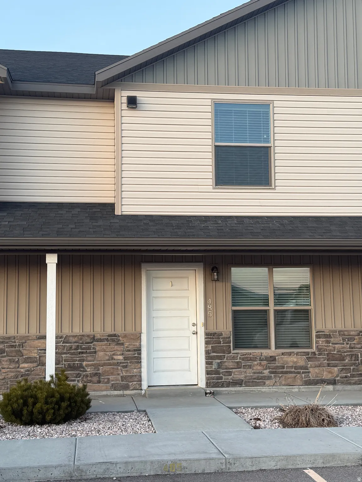 View of front of home with board and batten siding, stone siding, and roof with shingles
