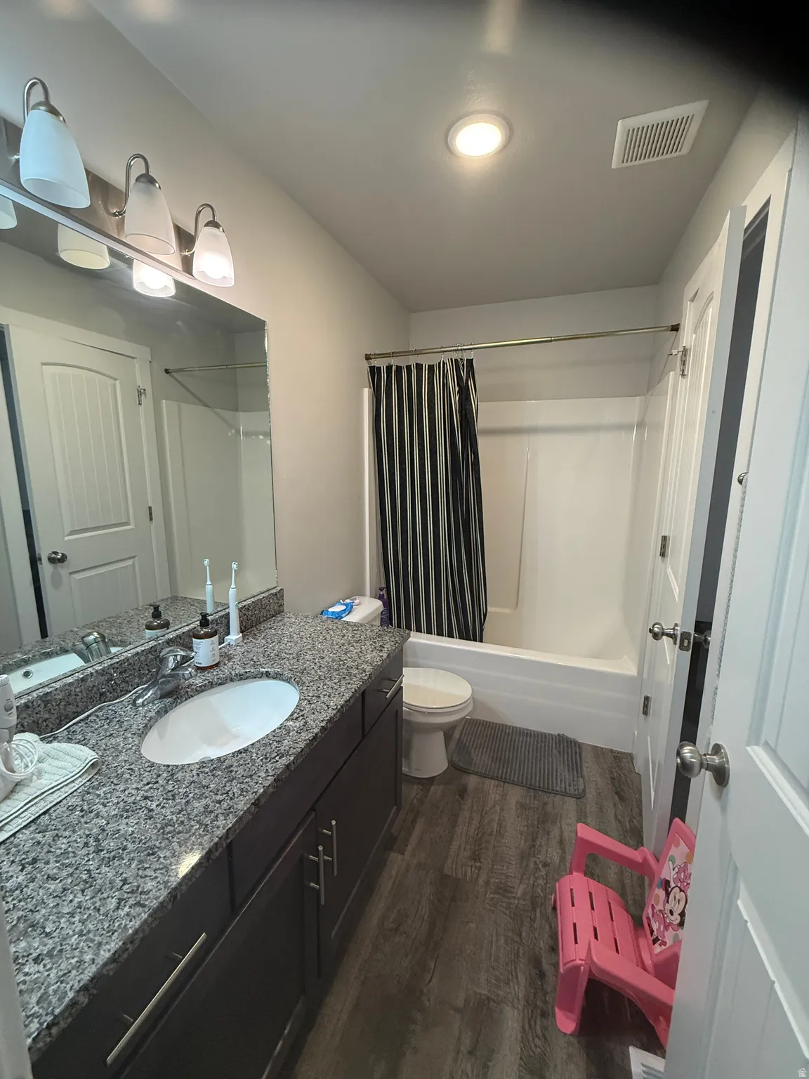 Bathroom featuring shower / bath combo, vanity, and dark wood-type flooring