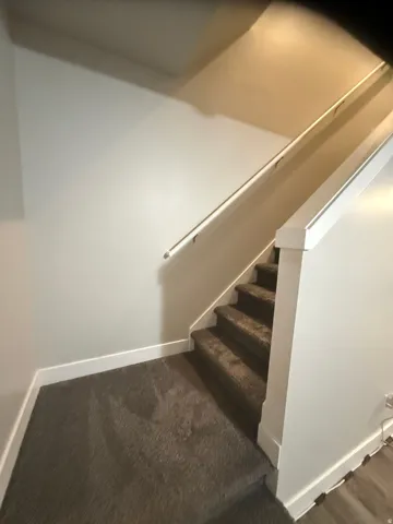 Stairway featuring baseboards and carpet flooring
